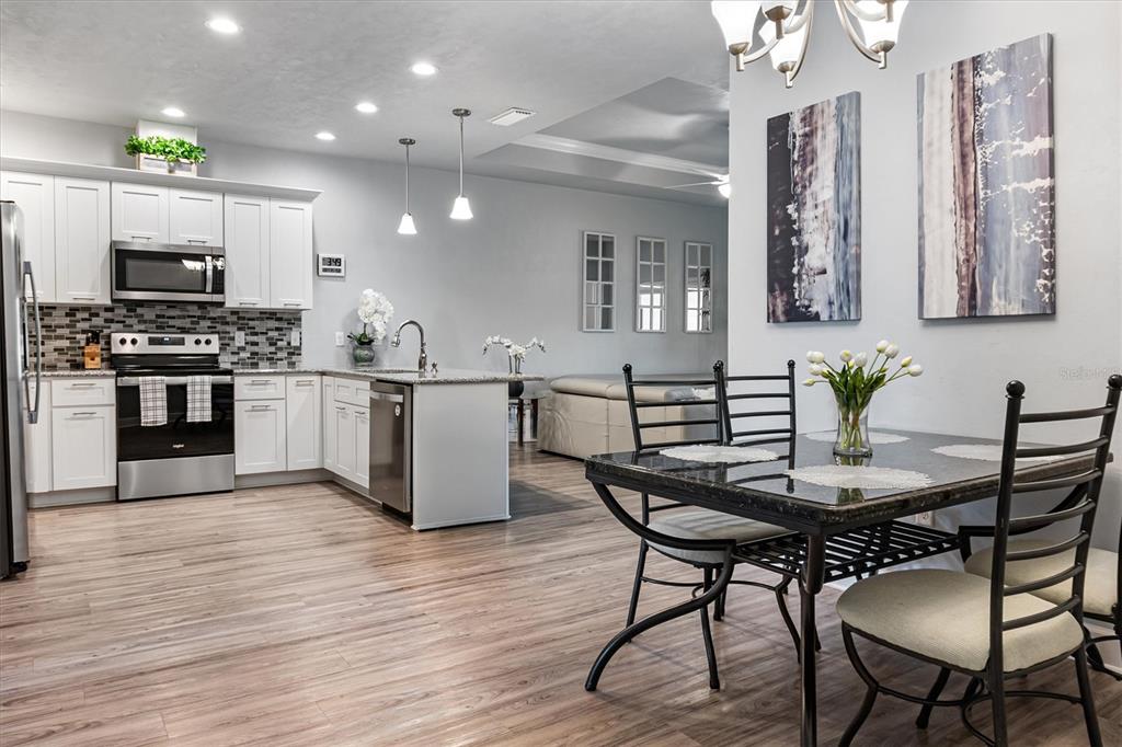 A kitchen with white cabinets and stainless steel appliances opens to a dining area — 1159 NW 129TH DRIVE, NEWBERRY, FL