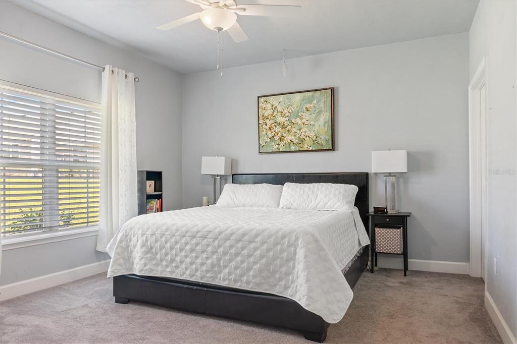 A bedroom features a bed with a white quilt, two nightstands, and a ceiling fan — 1159 NW 129TH DRIVE, NEWBERRY, FL