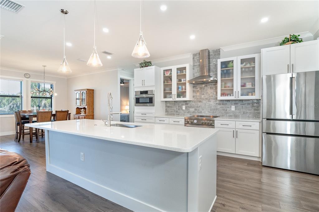 A modern kitchen features a large white island, stainless steel appliances, and gray subway tile — 237 W PINE VALLEY LANE, ROTONDA WEST, FL