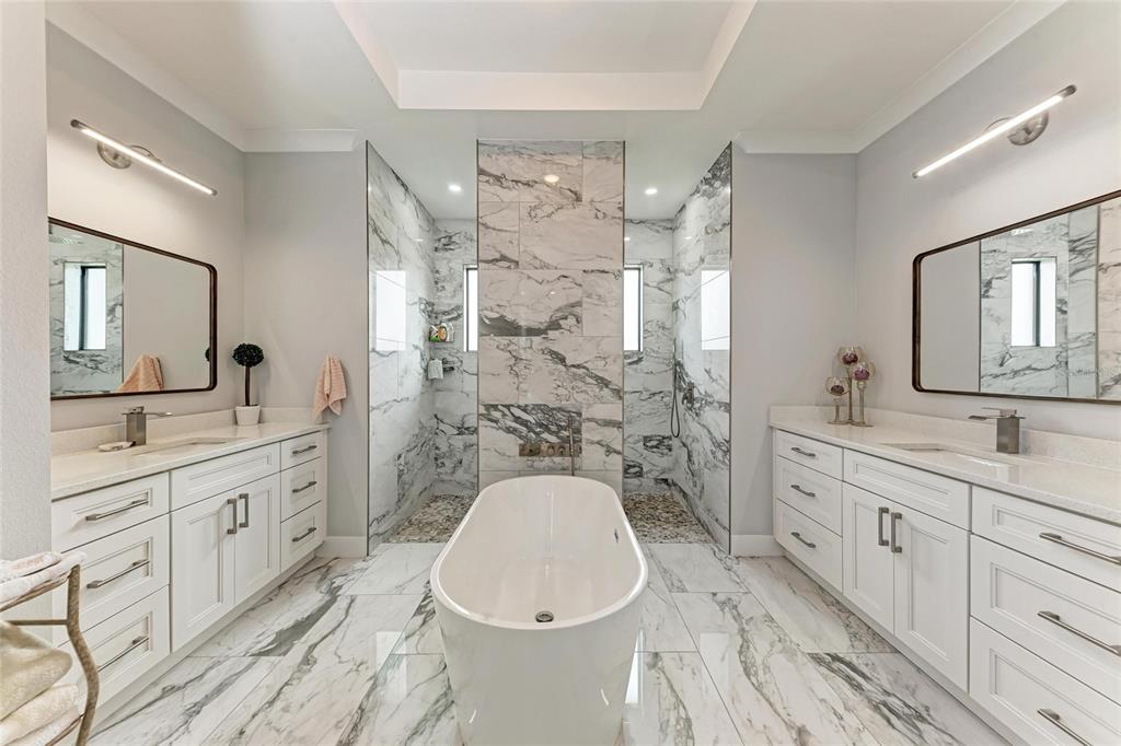 A primary bathroom features a freestanding tub, dual vanities, and a walk-in shower with marble — 237 W PINE VALLEY LANE, ROTONDA WEST, FL