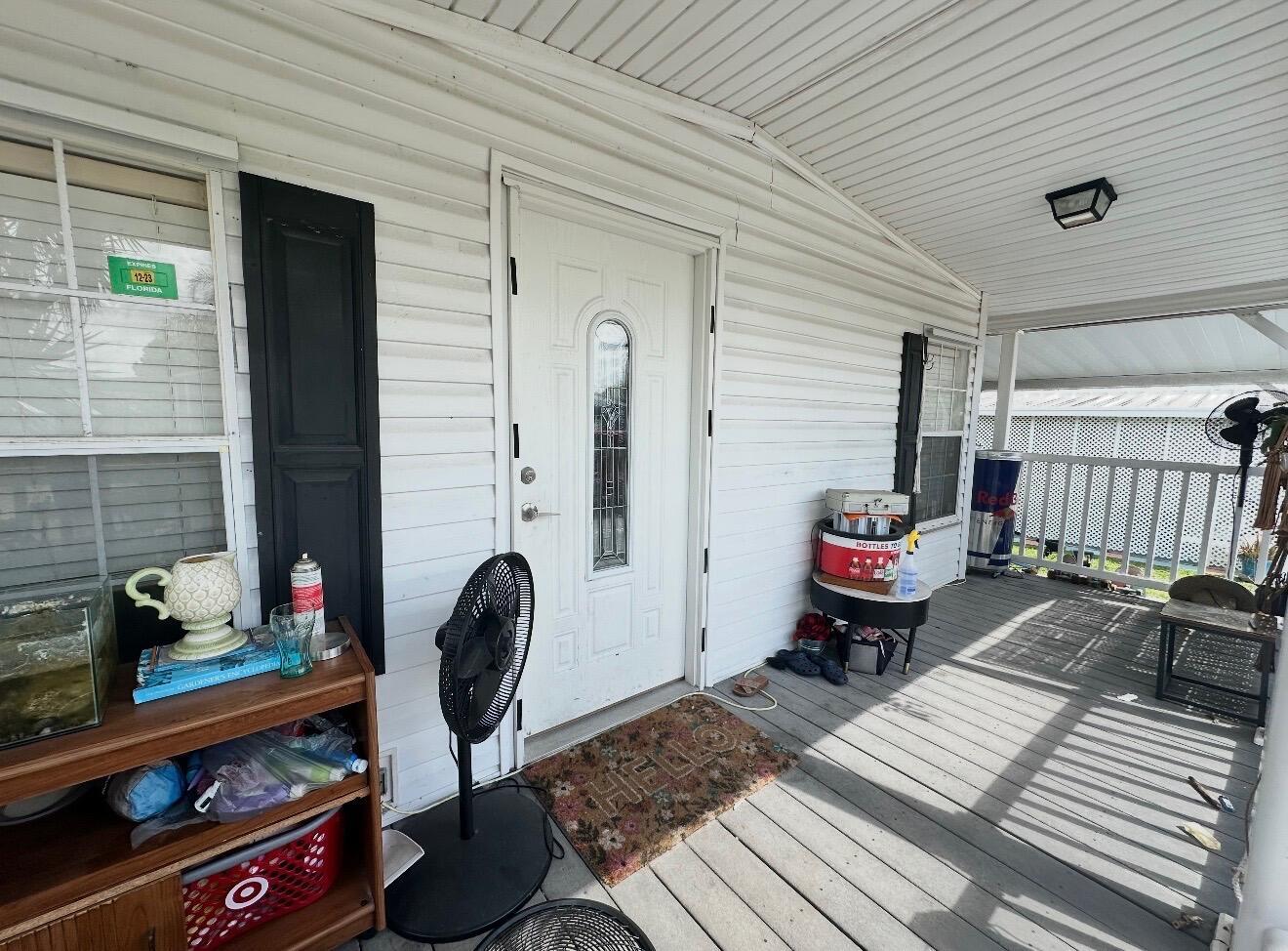 A white front door with a glass insert sits on a covered wooden porch — 1455 90th Avenue # 235, Vero Beach FL 32966, VERO BEACH, FL