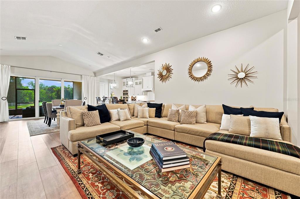 A living room features a large sectional sofa, a glass coffee table, and wall-mounted mirrors — 3333 ARMEN DRIVE, MERRITT ISLAND, FL