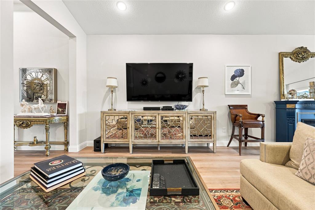 A living room features a wall-mounted television above a mirrored console table and wood flooring — 3333 ARMEN DRIVE, MERRITT ISLAND, FL