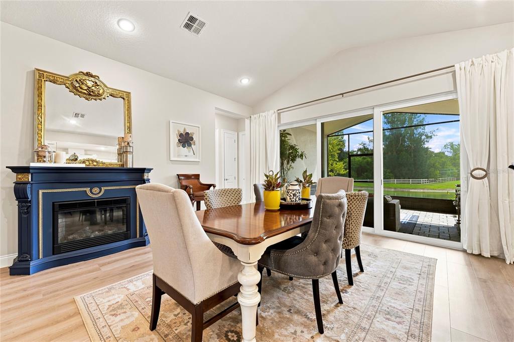 A dining room features a blue fireplace, wooden table, upholstered chairs, and sliding glass doors — 3333 ARMEN DRIVE, MERRITT ISLAND, FL