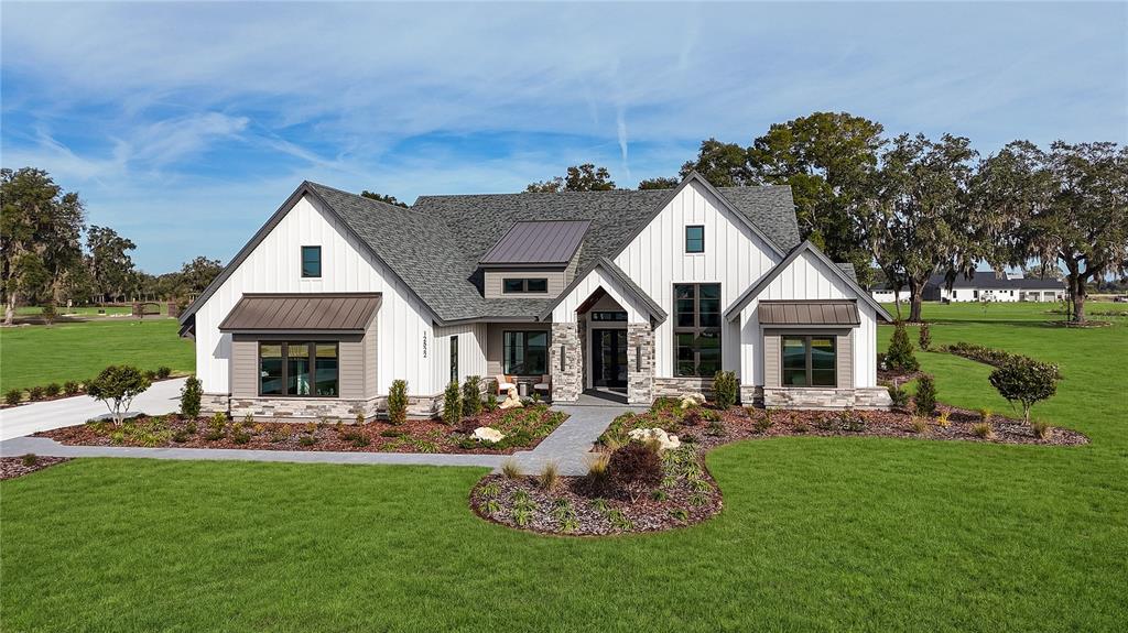 A modern farmhouse with white vertical siding, stone accents, and a dark metal roof — 12522 SW 58TH CIRCLE, ARCHER, FL