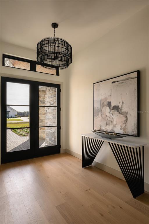 An entryway features light wood flooring, a modern black chandelier, and a geometric console table — 12522 SW 58TH CIRCLE, ARCHER, FL