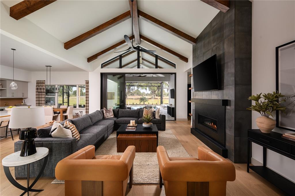 A living room features a vaulted ceiling with wood beams, a fireplace, and sliding glass doors — 12522 SW 58TH CIRCLE, ARCHER, FL