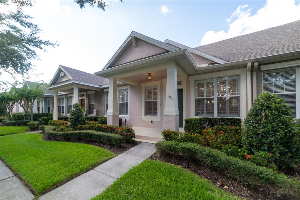 A light pink single-story house with a covered front porch and manicured landscaping — 13639 CEPHEUS DRIVE, ORLANDO, FL