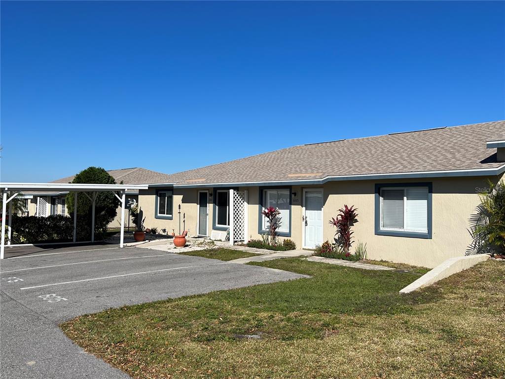 A single-story tan stucco duplex with a shingled roof and a shared carport — 605 RIDGE TERRACE UNIT 605, WINTER HAVEN, FL