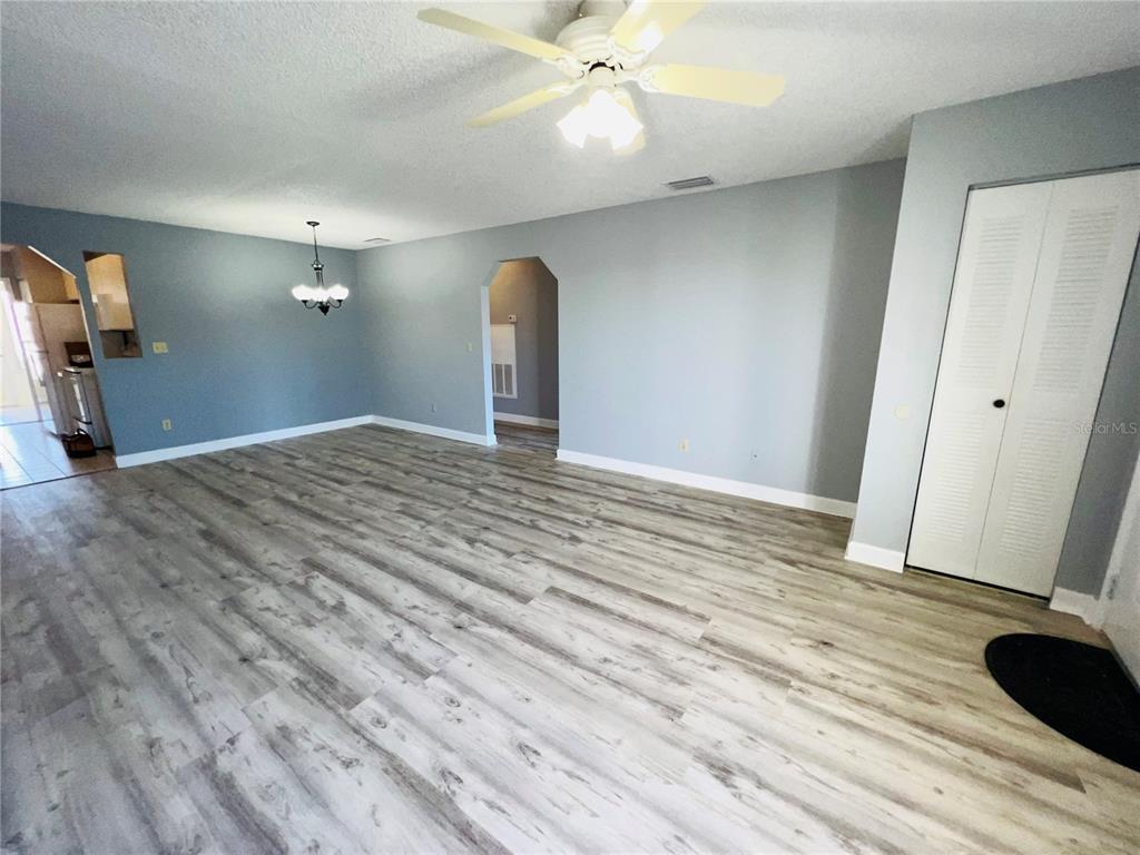 An open-concept living area features light gray walls, wood-look laminate flooring, and a ceiling fan — 605 RIDGE TERRACE UNIT 605, WINTER HAVEN, FL