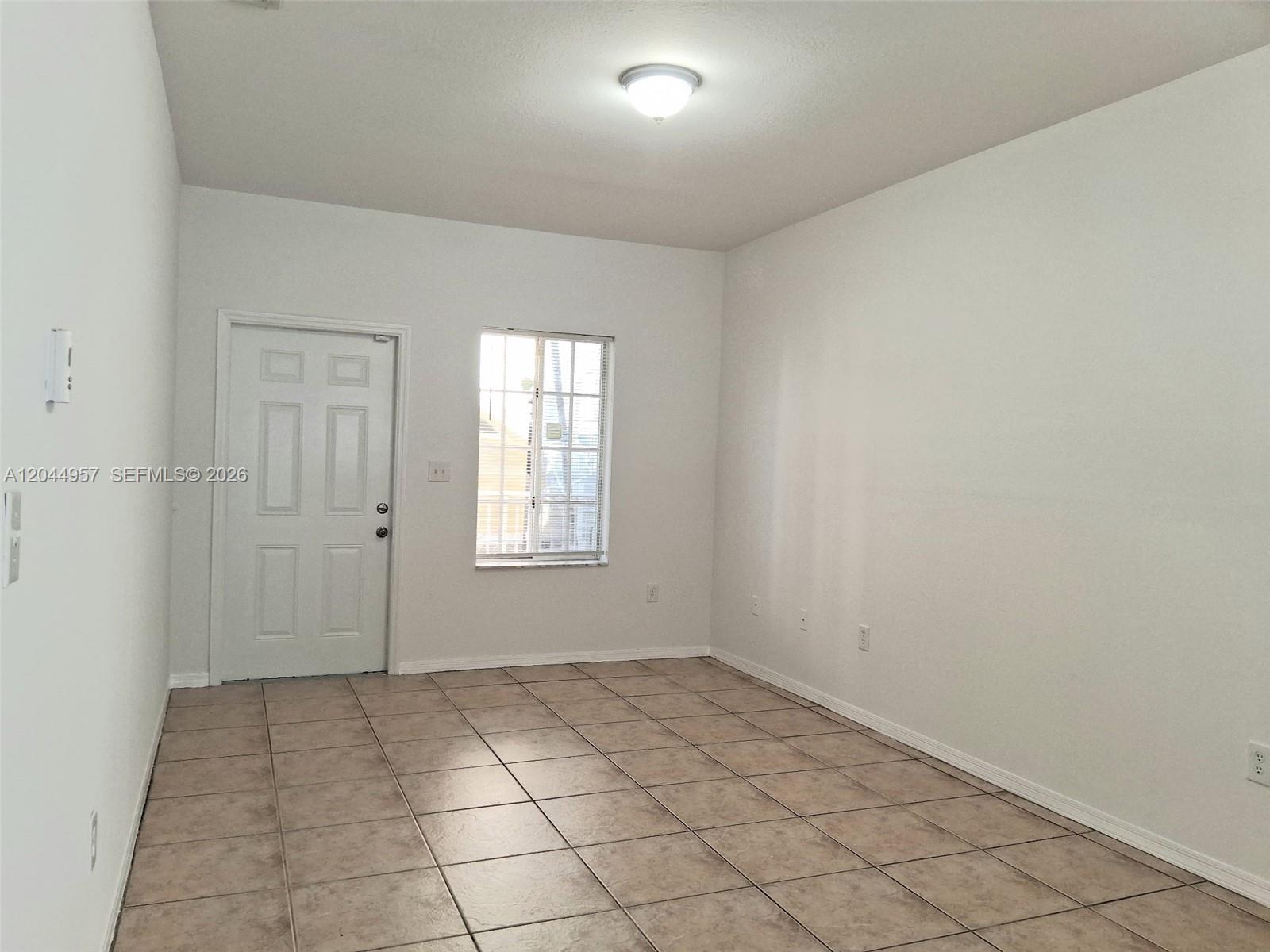 An empty room features white walls, a single window, a white door, and tiled flooring — 6972 NW 179th St # 4, Hialeah FL 33015, HIALEAH, FL