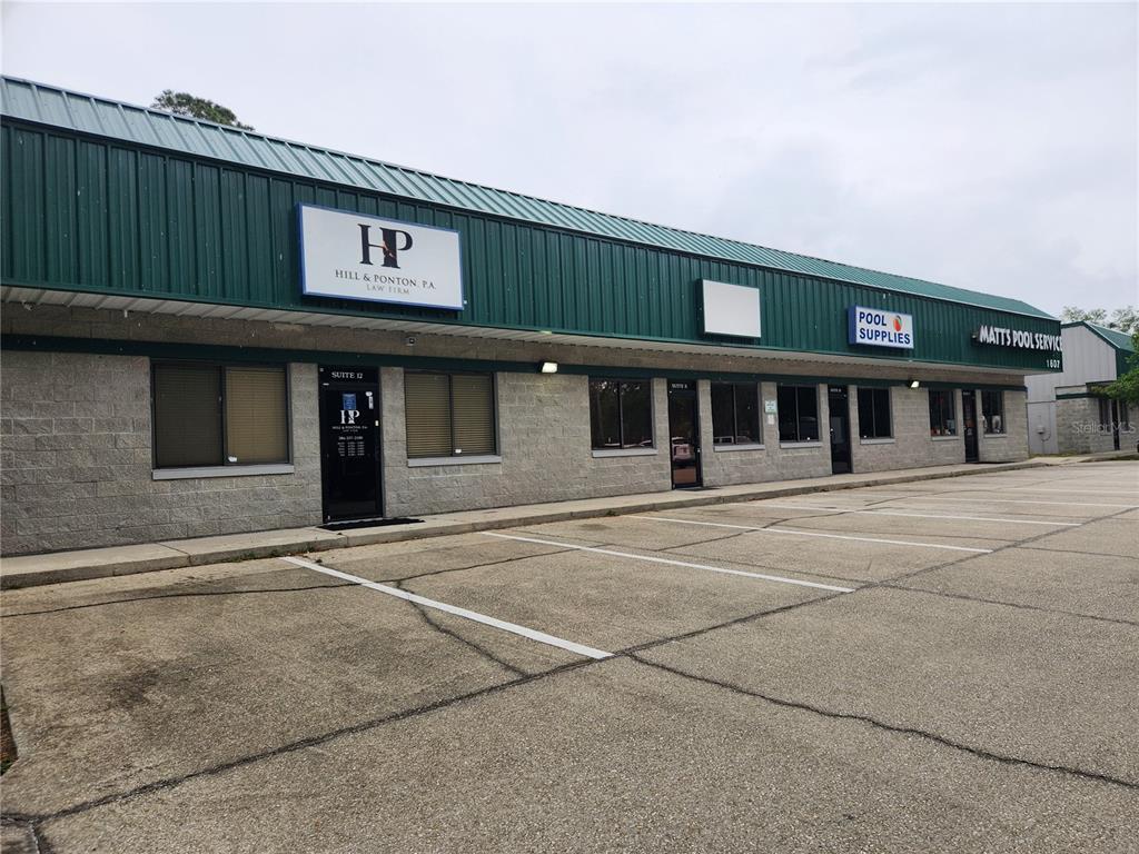 A single-story commercial building with a green metal roof and a paved parking lot — 1607 S STATE ROAD 15A UNIT 11, DELAND, FL