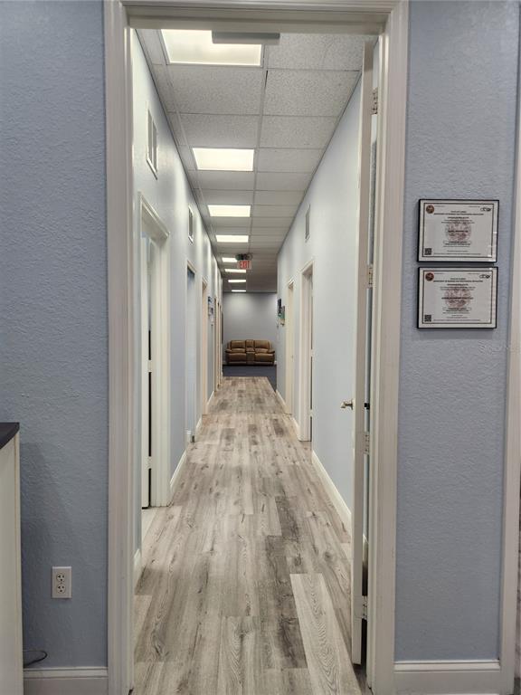 A hallway with light-colored wood-look flooring leads to a small seating area with a sofa — 1607 S STATE ROAD 15A UNIT 11, DELAND, FL