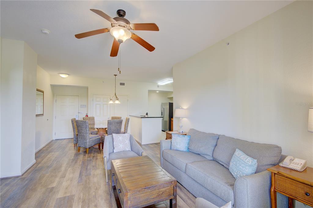 A living room with a gray sofa, wooden coffee table, and an adjacent dining area — 8101 RESORT VILLAGE DRIVE UNIT 31101, ORLANDO, FL