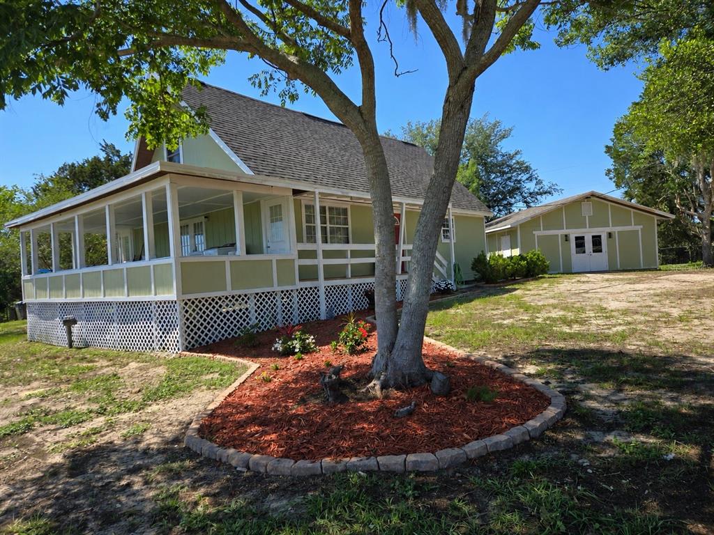 A light green house with a screened-in porch and a detached garage on a grassy lot — 13590 SE 120TH STREET, DUNNELLON, FL