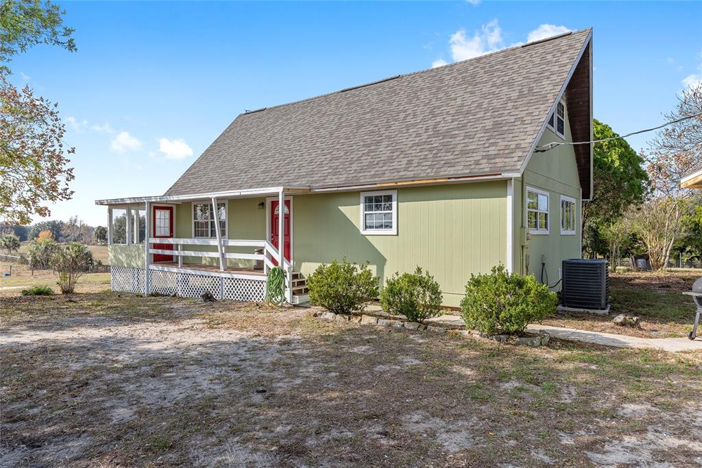 A light green house with a steep roof, a front porch, and a red door — 13590 SE 120TH STREET, DUNNELLON, FL
