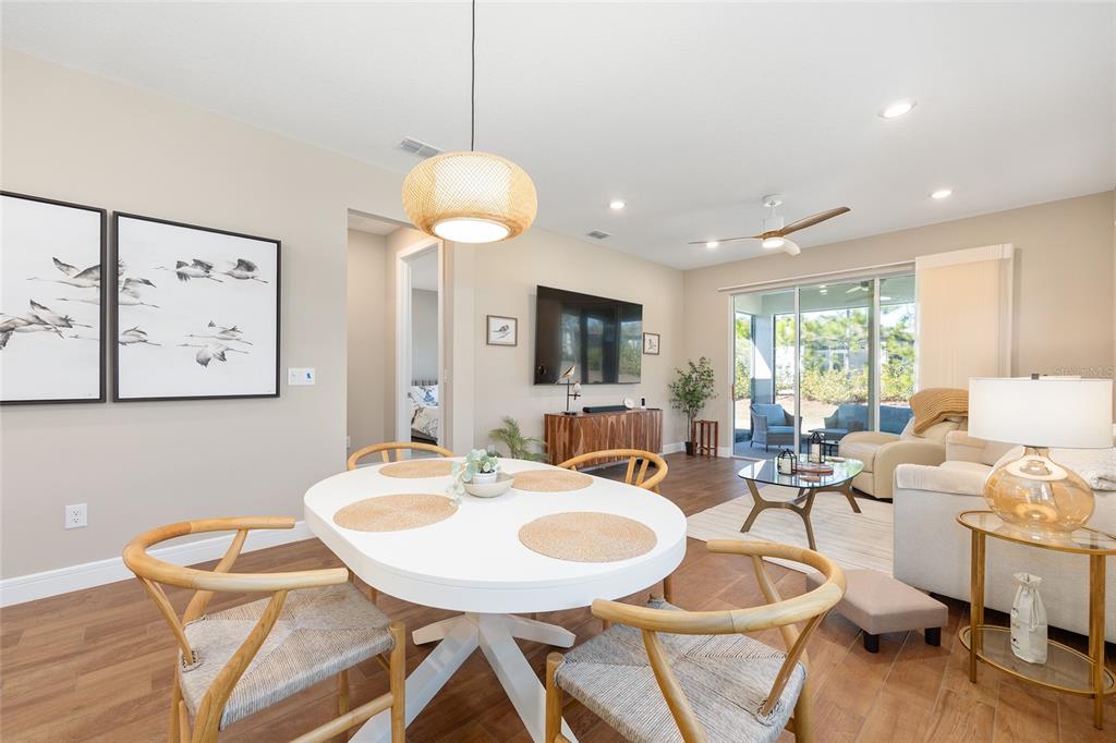 A dining area with a round white table opens into a living room with sliding doors — 8919 SW 58TH STREET ROAD, OCALA, FL