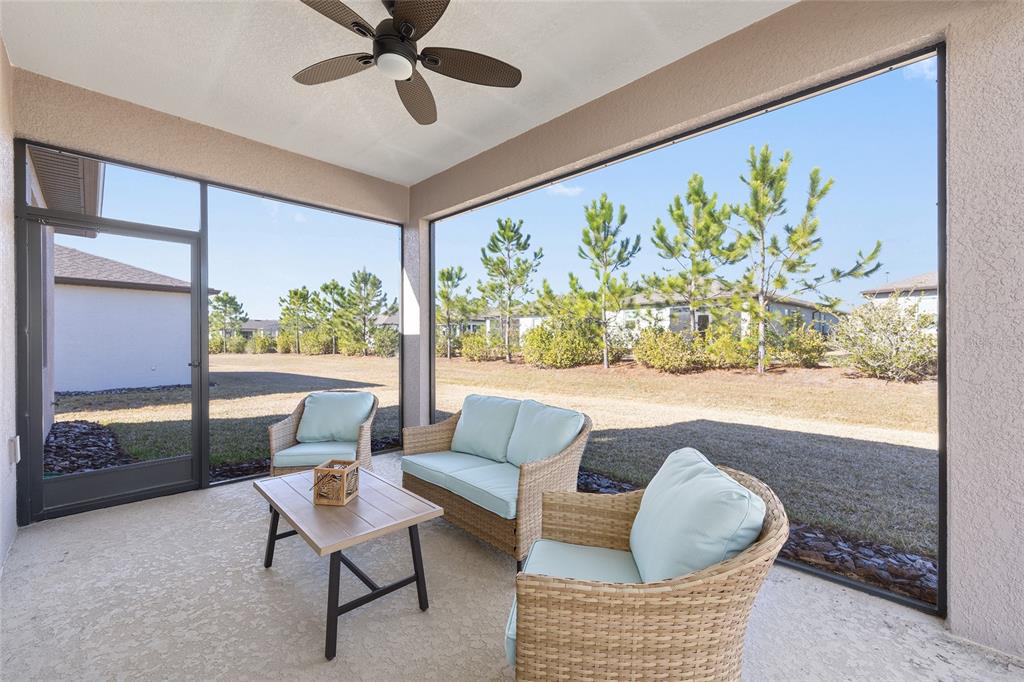 A covered patio features a wicker furniture set, a ceiling fan, and screened-in walls — 8919 SW 58TH STREET ROAD, OCALA, FL