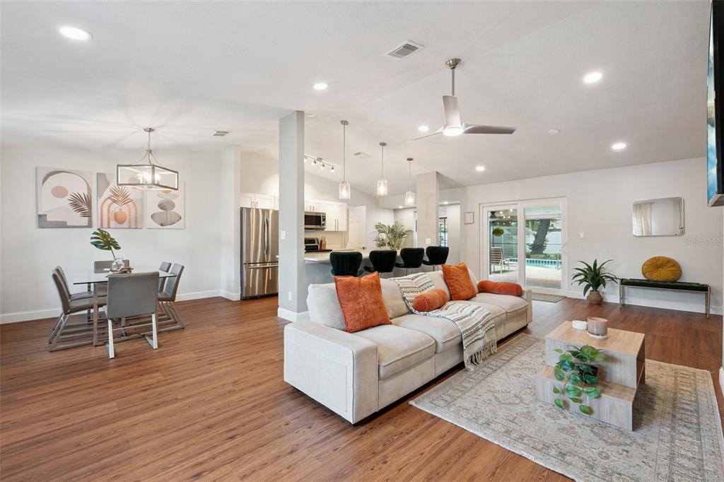 An open-concept living and dining area features wood-look flooring, a kitchen island, and sliding doors — 8714 HILL PINE ROAD, ORLANDO, FL