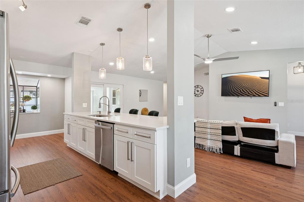 A kitchen with white cabinets and a stainless steel dishwasher opens to a living area — 8714 HILL PINE ROAD, ORLANDO, FL