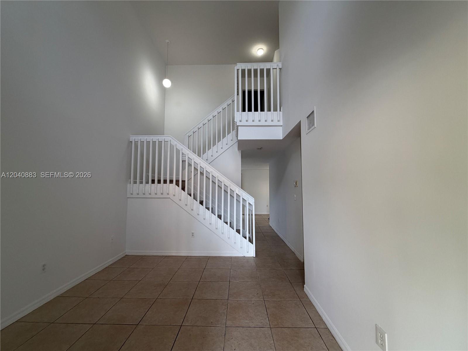 An interior view shows a tiled entryway with a white staircase and a high ceiling — 7245 NW 173rd Dr # 2505, Hialeah FL 33015, HIALEAH, FL