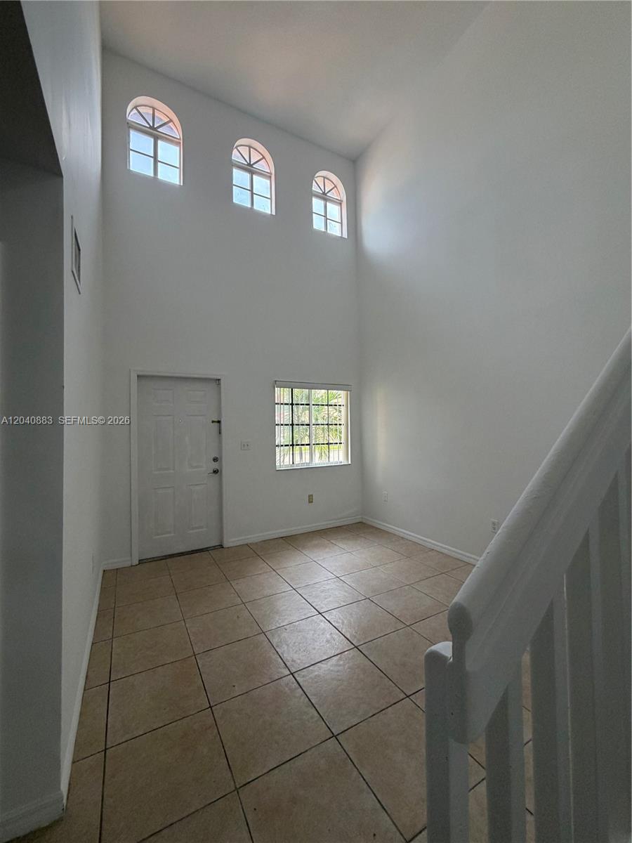 A high-ceilinged entryway features tiled floors, a white door, and arched windows — 7245 NW 173rd Dr # 2505, Hialeah FL 33015, HIALEAH, FL