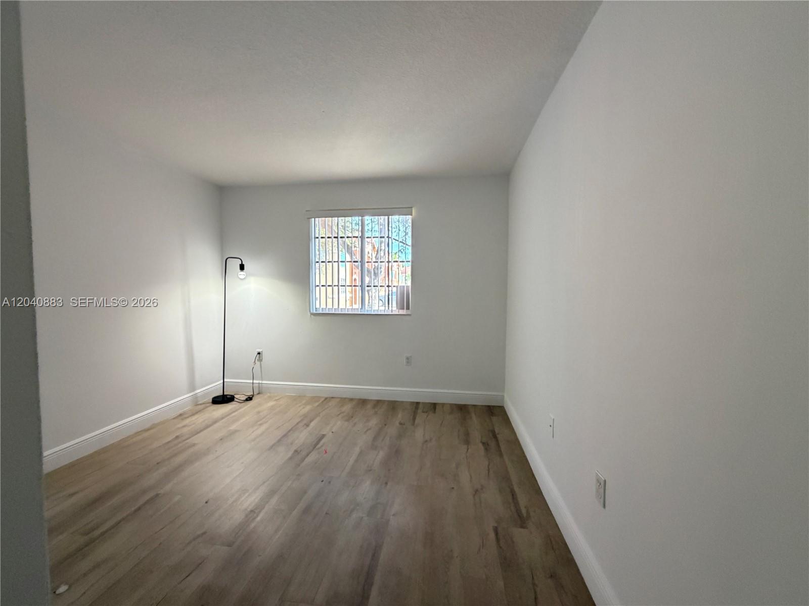 An empty room features light-colored wood-look flooring, white walls, and a single window — 7245 NW 173rd Dr # 2505, Hialeah FL 33015, HIALEAH, FL