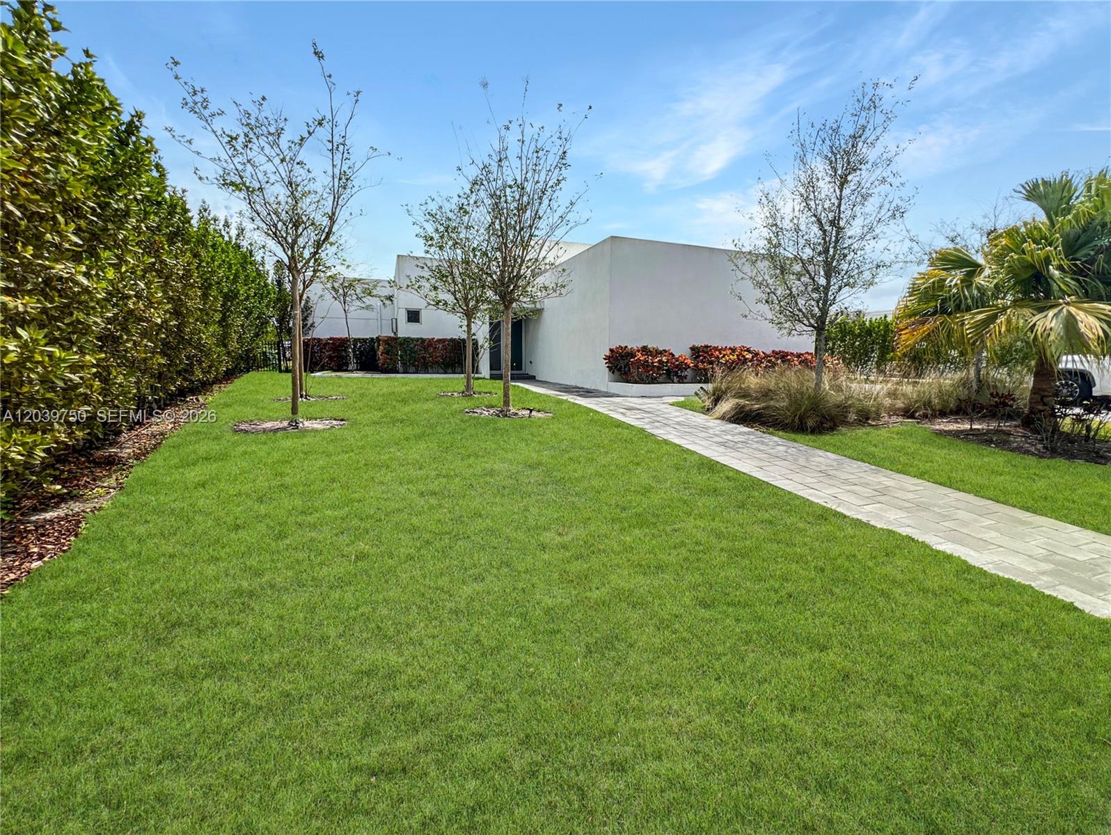 A modern white house features a paved walkway leading through a green lawn with trees — 16582 S Botaniko Dr S # 16582, Weston FL 33326, WESTON, FL
