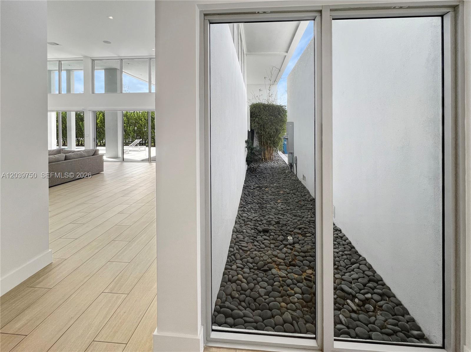 A bright living area with wood-look tile floors overlooks a narrow outdoor rock garden — 16582 S Botaniko Dr S # 16582, Weston FL 33326, WESTON, FL