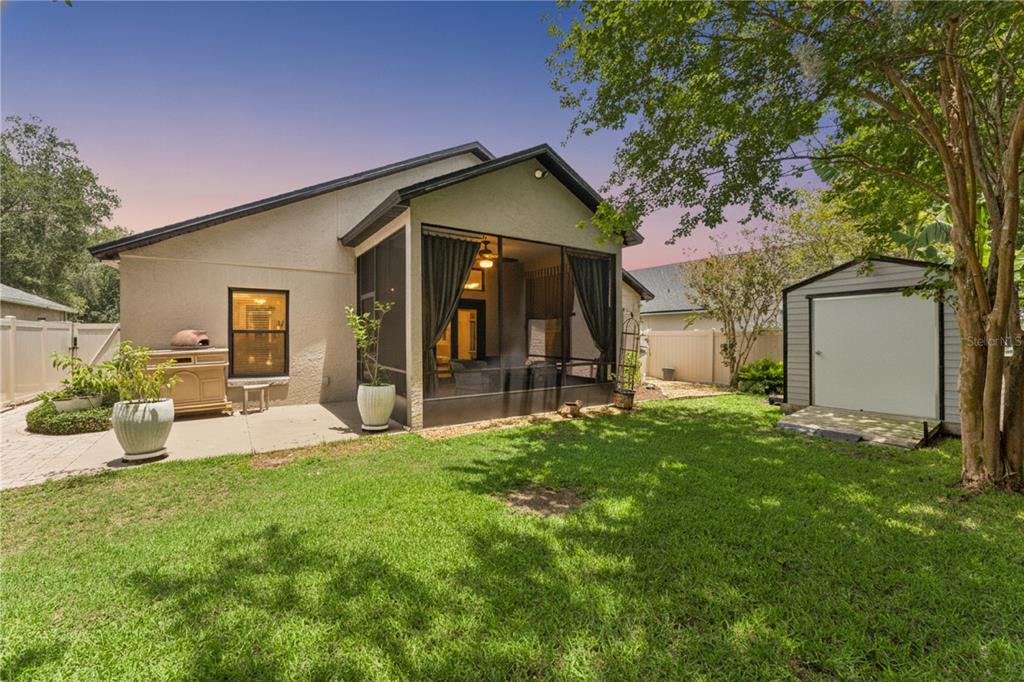 A backyard features a house with a screened-in porch, a concrete patio, and a storage shed — 293 KETTERING ROAD, DELTONA, FL