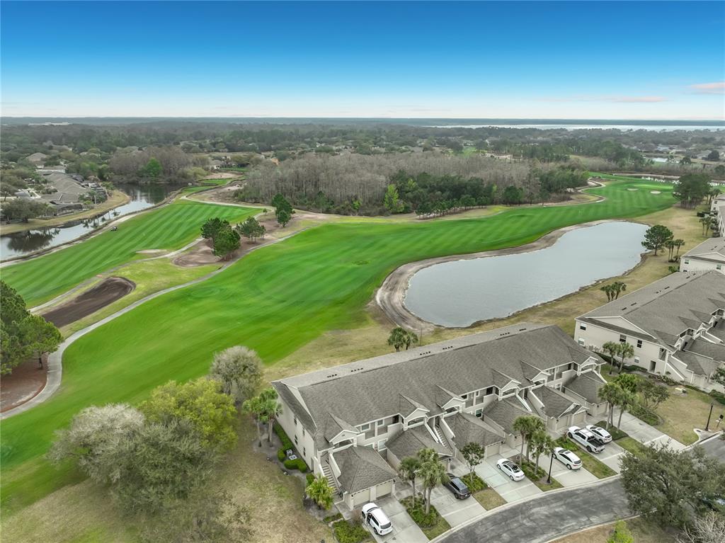 An aerial view shows a multi-unit townhouse complex overlooking a golf course and a pond — 9417 MYRTLE CREEK LANE UNIT 609, ORLANDO, FL