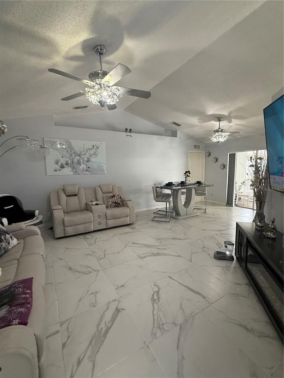 A living and dining area features white marble-look tile flooring and two crystal ceiling fans — 11435 PICKFORD STREET, SPRING HILL, FL