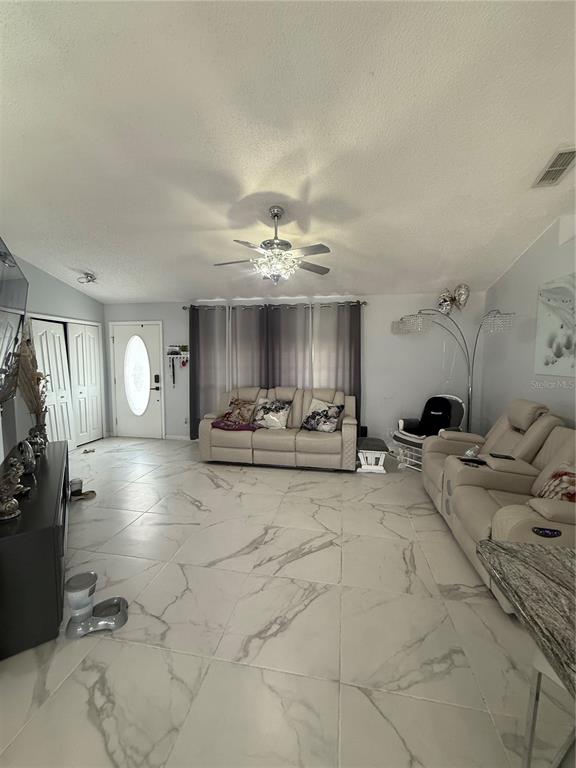 A living room features light-colored tile flooring, a beige sofa, and a ceiling fan — 11435 PICKFORD STREET, SPRING HILL, FL