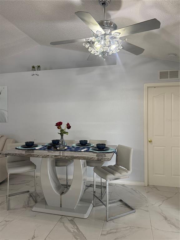 A dining area features a modern table with four chairs under a crystal ceiling fan — 11435 PICKFORD STREET, SPRING HILL, FL