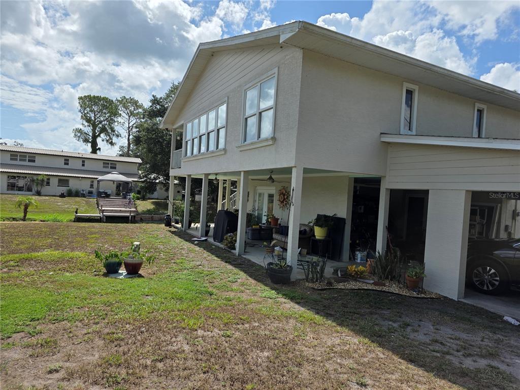 The exterior of a two-story house features a covered ground-level patio and a grassy yard — 14365 SE 107TH AVENUE, SUMMERFIELD, FL