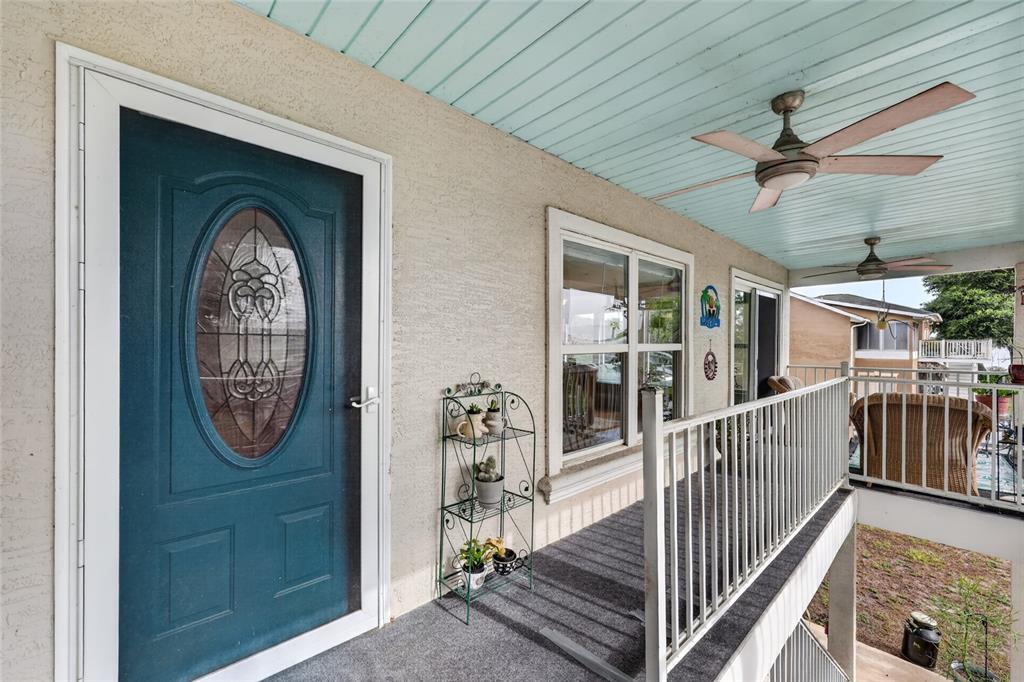A covered balcony features a blue front door, a ceiling fan, and a metal railing — 14365 SE 107TH AVENUE, SUMMERFIELD, FL