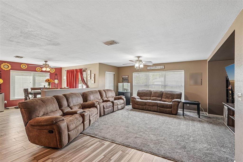 A living room features brown reclining sofas, carpeted flooring, and an adjacent dining area — 2279 MISTLETO LANE, NORTH PORT, FL