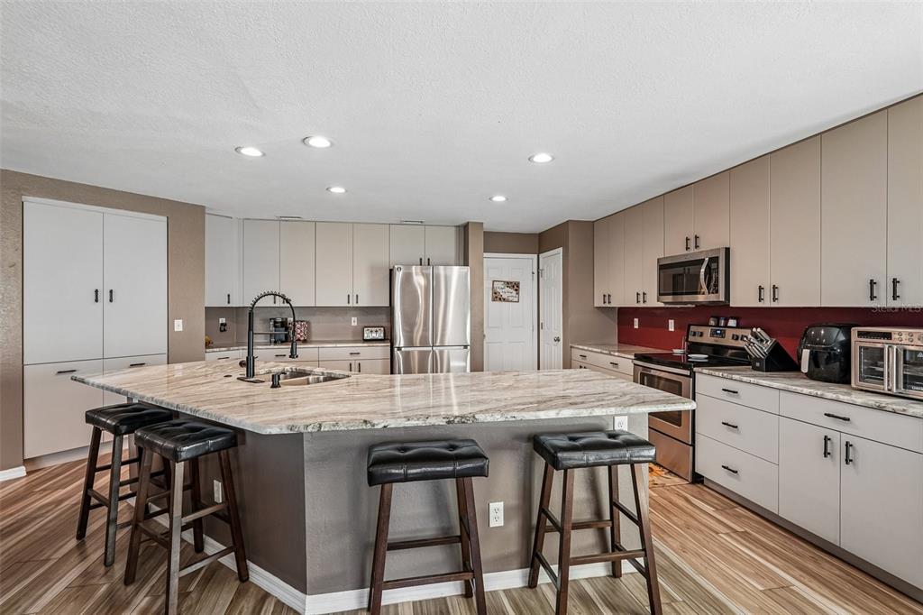 A kitchen features a large granite island, stainless steel appliances, and light-colored cabinetry — 2279 MISTLETO LANE, NORTH PORT, FL