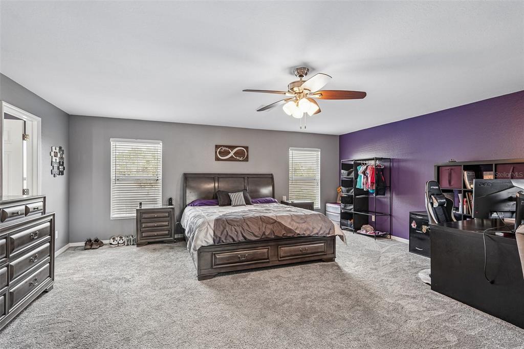 A bedroom features a dark wood bed, gray walls, a purple accent wall, and carpet — 2279 MISTLETO LANE, NORTH PORT, FL