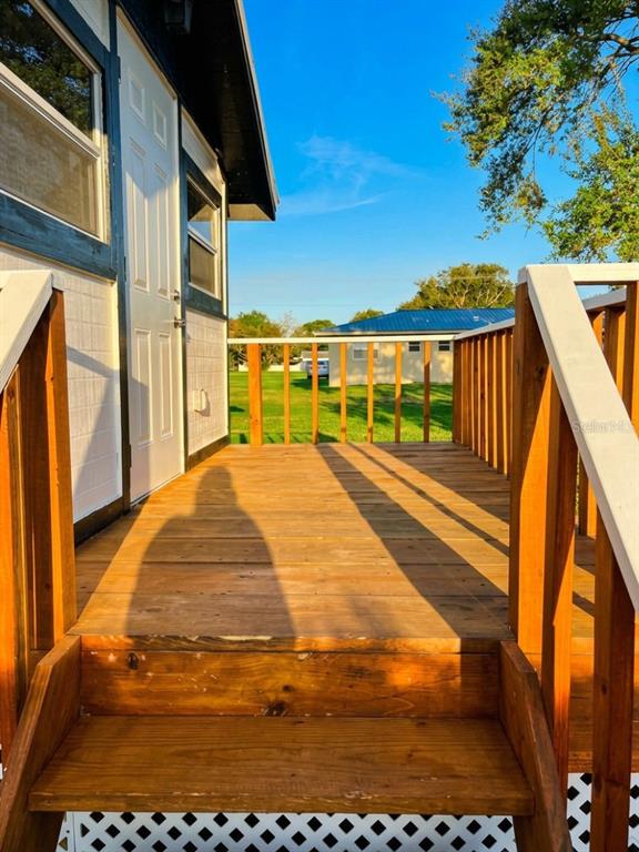 A wooden deck with stairs leads to the side entrance of a small white building — 3420 AVENUE R NW, WINTER HAVEN, FL
