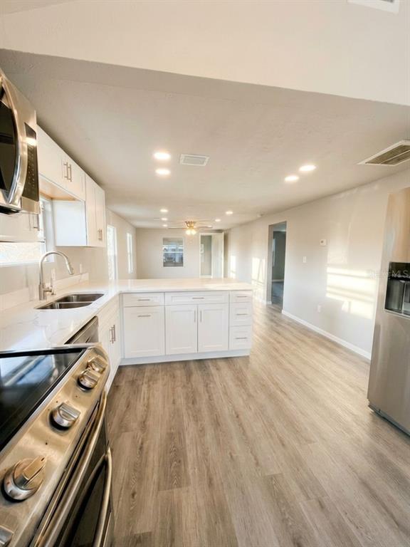 A kitchen with white cabinets, stainless steel appliances, and light wood-look flooring — 3420 AVENUE R NW, WINTER HAVEN, FL