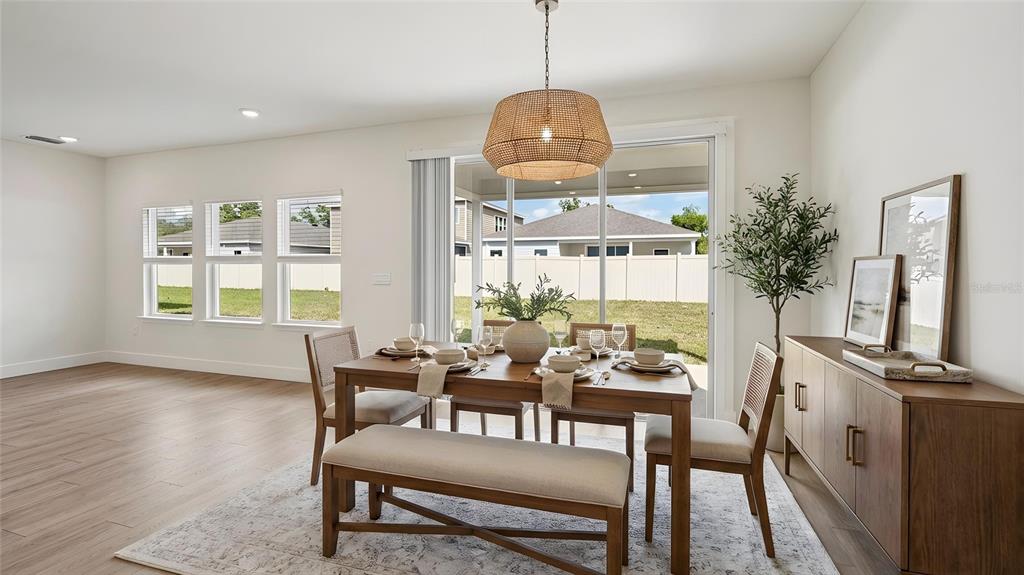 A dining room features a wooden table, a bench, chairs, and a woven pendant light — 11225 DUCKLING WAY, WEEKI WACHEE, FL