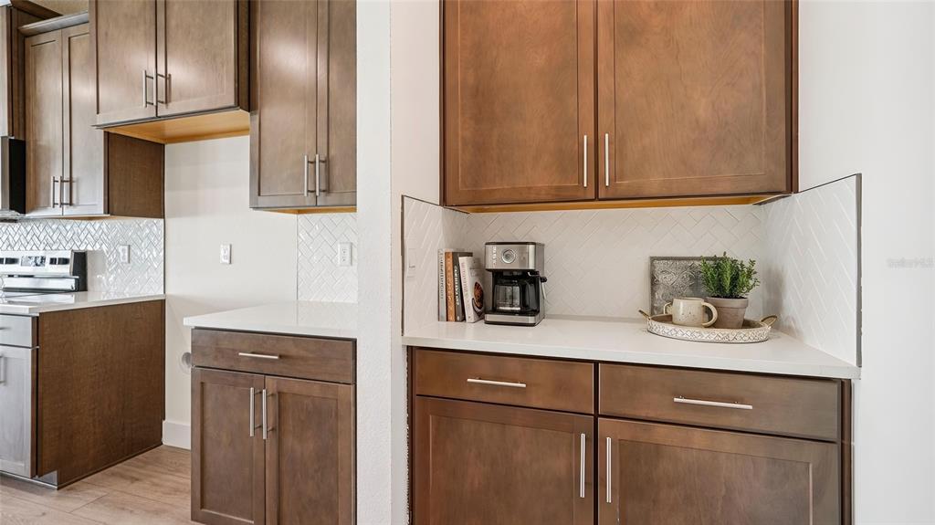 A kitchen features dark wood cabinets, white countertops, and a white herringbone tile backsplash — 11225 DUCKLING WAY, WEEKI WACHEE, FL
