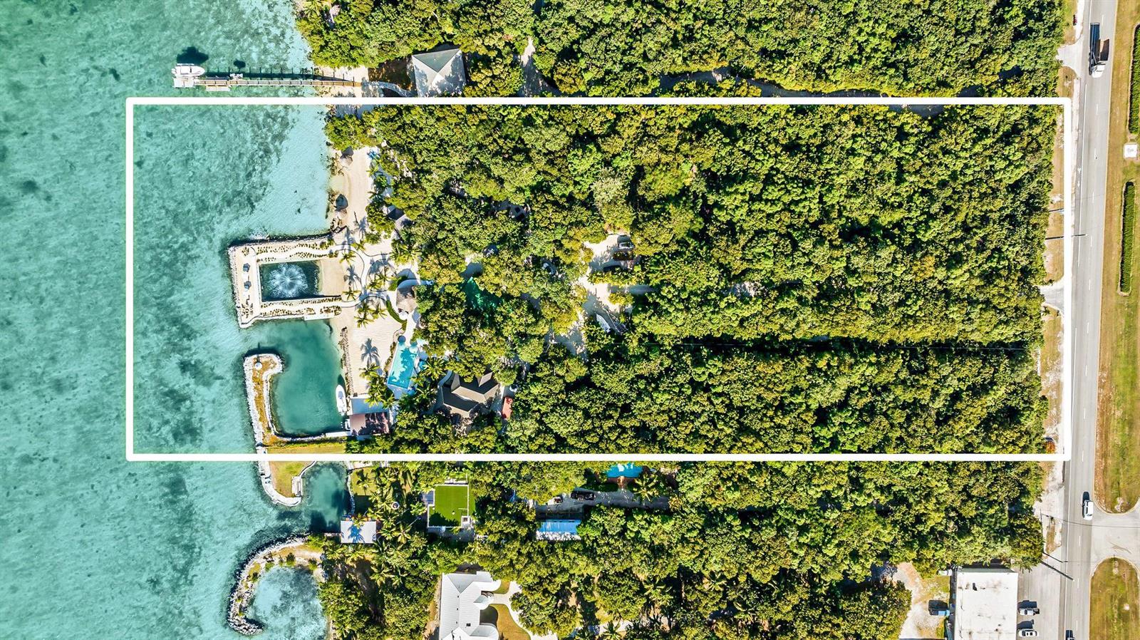 An aerial view shows a waterfront property with a private dock, pool, and dense vegetation — 95410 Overseas Highway, Key Largo FL 33037, KEY LARGO, FL
