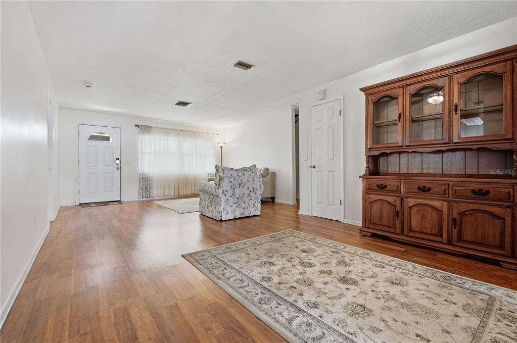 A living room features wood-look flooring, a large wooden hutch, and a floral armchair — 527 BOUNTY AVENUE NE, PALM BAY, FL