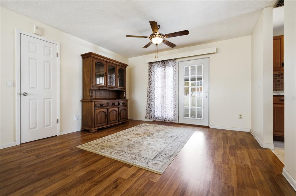A dining room with wood-look flooring, a wooden hutch, a ceiling fan, and a glass door — 527 BOUNTY AVENUE NE, PALM BAY, FL