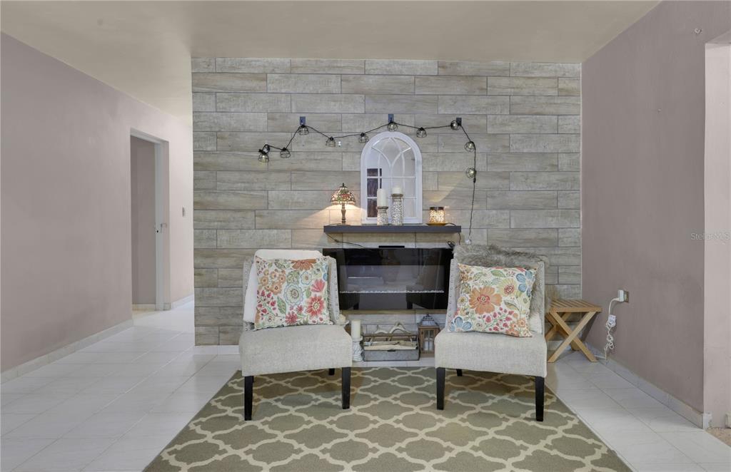 A living room features a fireplace with a wood-look tile wall and two armchairs — Comm Cienguetas #33 BO ESPERANZA, ARECIBO, PR