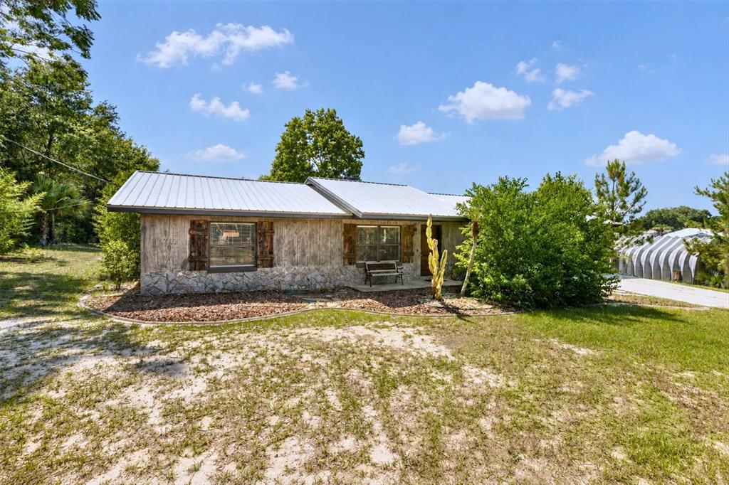 A single-story house with wood siding, a stone base, and a metal roof — 37149 GRAYS AIRPORT ROAD, LADY LAKE, FL