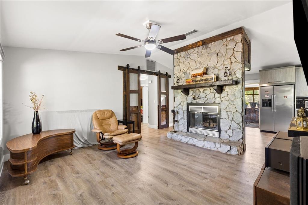 A living room features a stone fireplace, a ceiling fan, and a tan leather recliner — 37149 GRAYS AIRPORT ROAD, LADY LAKE, FL