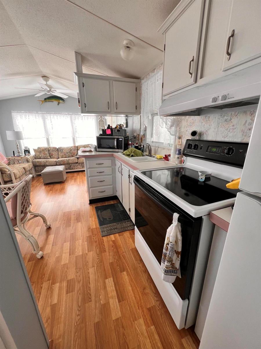 A kitchen with white cabinets and a black electric stove opens into a living area — 1361 Overseas Highway # G15, Marathon FL 33050, MARATHON, FL